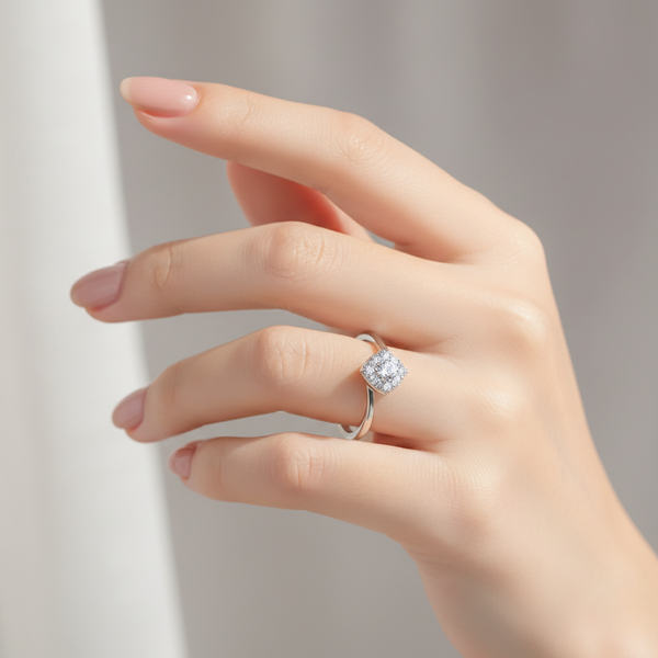 Hand wearing a silver ring with a diamond on a neutral background