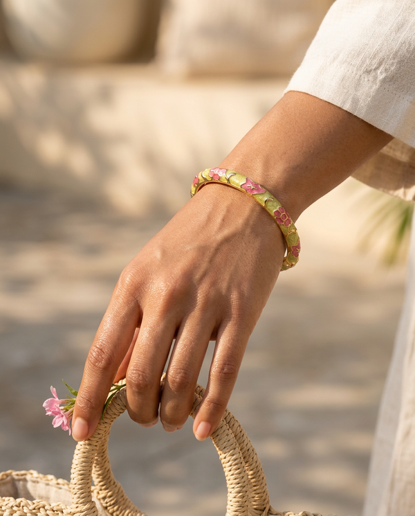 Pink and green enamel maple-leaf bangle worn on the wrist, summer