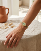 Gold oval gemstone crystal-link watch with green dial worn on the wrist, summer
