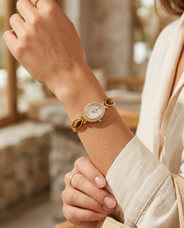 Gold Roman-numeral watch with brown strap worn on the wrist, summer editorial