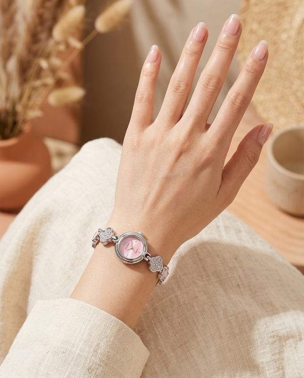 Silver floral-design watch with soft pink face worn on the wrist, summer