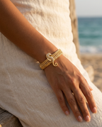 Gold marine pearl conch bangle worn on the wrist, coastal summer