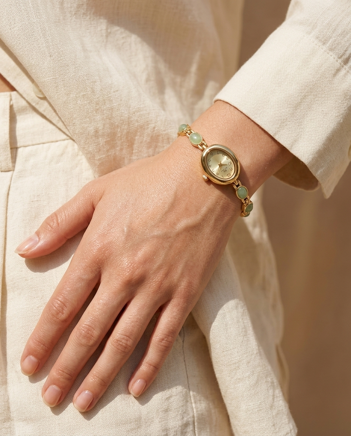Gold oval-dial stone watch with green face worn on the wrist, summer editorial