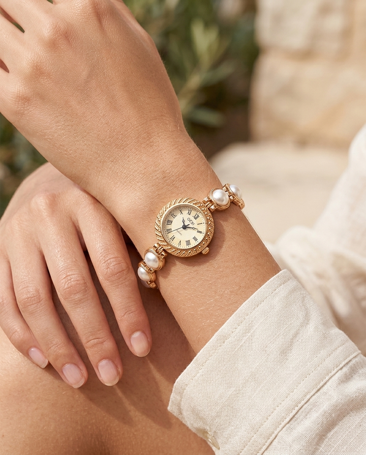 Gold textured-bezel Roman-dial watch with white pearl face worn on the wrist, summer